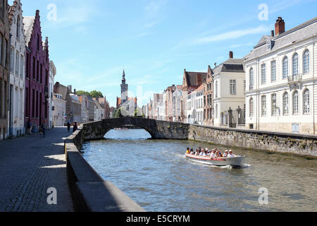 Touristen auf einem Boot Reise auf dem Kanal von Brügge, Belgien. Das alte Zollhaus im Hintergrund. Stockfoto