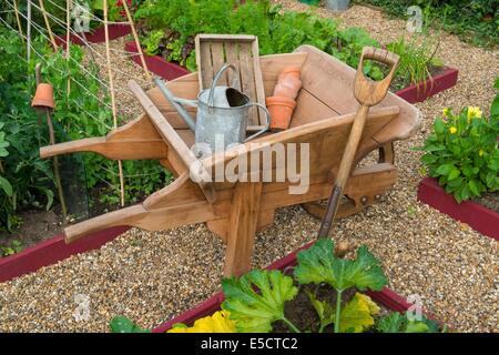 Blick auf kleine Hochbeet Pflanzen mit Sommerkulturen und traditionellen hölzernen Schubkarre, England Juli. Stockfoto