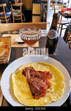 Orval Trappist Belgian Ale-Flasche und Glas auf einem Tisch mit Speck und Eiern Stockfoto