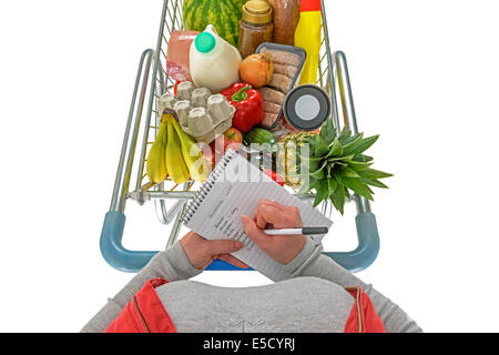 Overhead Foto einer Frau ihre Einkaufsliste mit einem Wagen voller frische Lebensmittel, auf einem weißen Hintergrund. Stockfoto