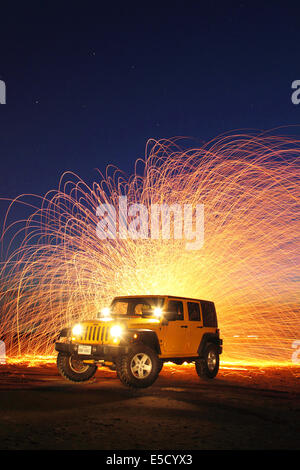 Funken aus eine spinnende Kugel Stahlwolle Fliege hinter einem 2008 Jeep Wrangler X unbegrenzt am Strand. Stockfoto