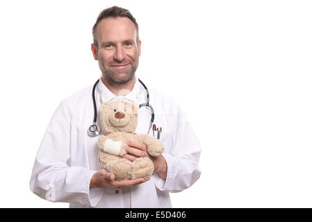 Freundlich lächelnd mittleren Alters männlichen Kinderarzt mit unrasierten Stoppeln halten einen Teddybär mit einem bandagierten Arm Videoprüfung zu beruhigen Stockfoto