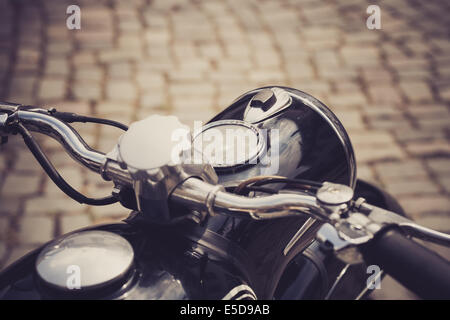 ein Oldtimer Motorrad mit einer gepflasterten Straße im Hintergrund Stockfoto