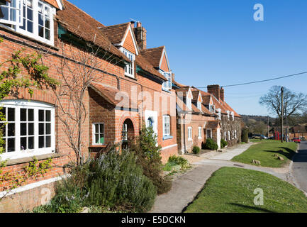 Reihe von traditionellen attraktiven ländlichen roten Backsteinterrassenhäusern im Dorf Great Bedwyn, Wiltshire, Großbritannien an einem sonnigen Tag mit einem blauen Himmel Stockfoto