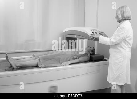 Frau in 40er Jahren Prüfung in Knochen Densitometer Maschine mit Reife Frau Arzt unterziehen. Stockfoto