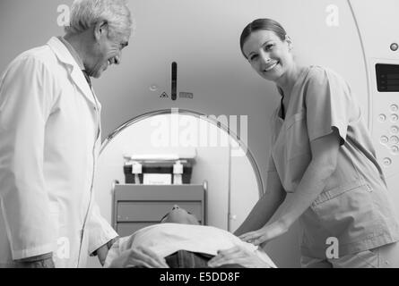 Mann in 40er Jahren offene MRT-Untersuchung unterziehen, männlichen und weiblichen Arzt lächelt ihn an. Stockfoto