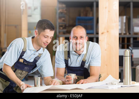 Zwei Handwerker mit Metall Tassen sprechen Stockfoto