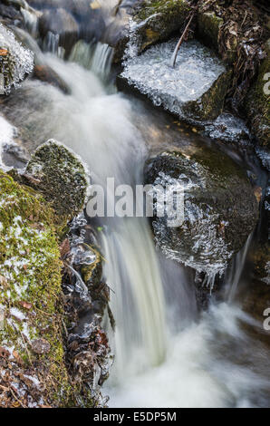 Kleiner Wasserfall mit Eiszapfen und Eis in der Nähe bis Frühling. Stockfoto