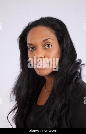 Frau mit langen Haaren, trägt eine dunkle Bluse, mit einem freundlichen Lächeln in die Kamera schaut ziemlich schwarz Stockfoto