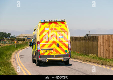 Rückansicht eines Krankenwagens auf einer Landstraße mit Blaulicht blinkt, Reaktion auf einen Notruf Stockfoto