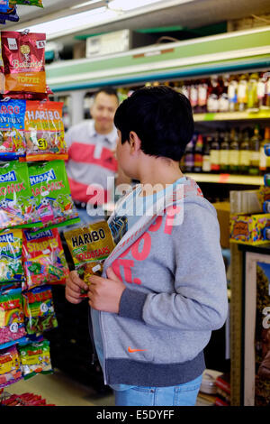 kleiner Junge Ladendiebstahl Süßigkeiten in einen kleinen Mini-Markt Stockfoto
