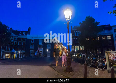 amsterdam, Holland, Niederlande, Straßenszene, verbrauchsarme LED-Beleuchtung, Straßenlampe, paar Touristen besuchen, Stadtstraße bei Nacht Stockfoto