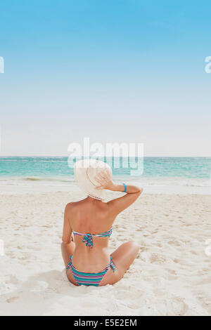 Eine junge Frau sitzt an einem Strand in der Karibik Stockfoto