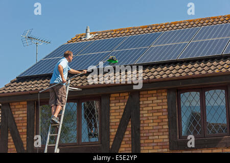 Reinigung angesammelten Schmutz, Dreck und Vogelkot von Sonnenkollektoren auf dem Dach Photovoltaik (PV). JMH6246 Stockfoto