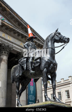 Glasgow, Schottland, Großbritannien. 29. Juli 2014. Kevin Powell, eine Straße und Pantomime von Cheshire, England zeigt einige Unternehmertum durch die Nachahmung Glasgow's iconic Statue des Herzogs von Wellington mit einem Parkplatz Kegel auf den Kopf durch das Sitzen auf einem kleinen hölzernen Pferd in Buchanan Street Fußgängerzone. Der Herzog von Wellington Statue ist eine erkennbare Symbol von Glasgow Humor und Kevin Powell's Mocking erstellt eine ungeheure Menge von Interesse und Lachen. Einen großen Nachbildung der Statue wurde während der Eröffnung der Commonwealth Games verwendet. Credit: Findlay/Alamy leben Nachrichten Stockfoto