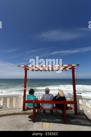 Drei Frauen sitzen auf einer schattigen Bank Blick aus Meer bei Silverira, Portugal Stockfoto