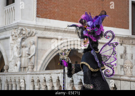 Frau in stilisierten buttrige Kostüm Schwarz mit Lavendel auf der Brücke von der Dogenpalast während des Karnevals in Venedig. Stockfoto