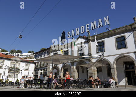 Menschen entspannend außerhalb des Sandeman port Wein Gebäude in Gaia Portugal. Die Teleferico de Gaia tourpreis Auto vorbei an Overhead Stockfoto