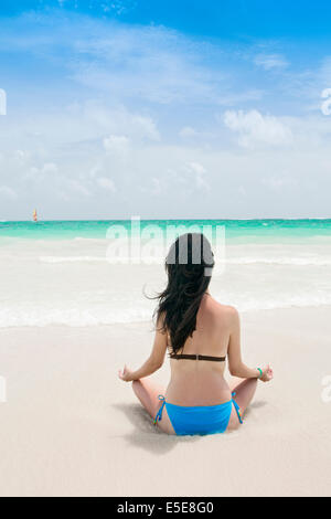 Eine junge Frau sitzt an einem Strand in der Karibik Stockfoto