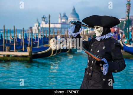 Carnival Sea Captain in Schwarz schaut durch Teleskop am Ufer der Lagune von Venedig. Stockfoto