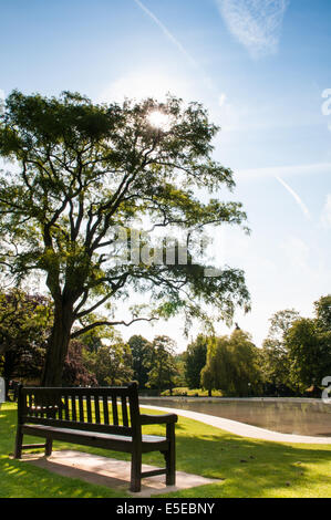 Leer ruhige Parkbank mit Blick auf hübsche Tettenhall Planschbecken im frühen Morgen sommer sonne Stockfoto