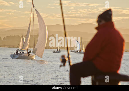 Segelboote und Angler bei Sonnenuntergang am Santander Bucht. Stockfoto