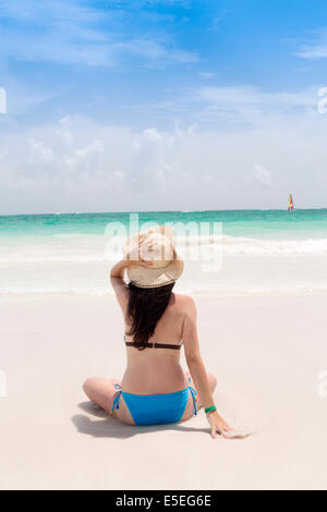 Eine junge Frau sitzt an einem Strand in der Karibik Stockfoto