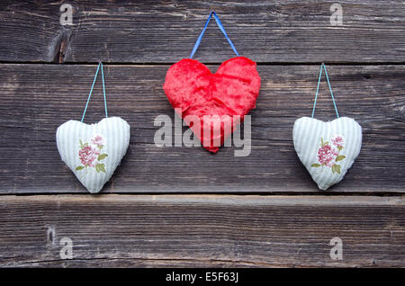 drei bunte Tuch Herz Symbole auf alte Holzwand Stockfoto