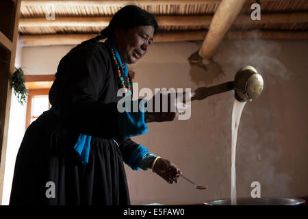 Eine Ladakhi Frauen in traditioneller Tracht machen tibetischen Buttertee. Stockfoto