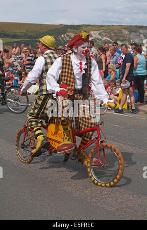 Swanage Carnival Parade Prozession in Swanage, Dorset UK im Juli mit dem Motto „Celebrate Britain“: Clowns treten auf einem Spezialfahrrad auf Stockfoto