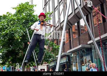 Straße Straßenmusiker spielen eine Geige beim Ausführen auf einem Trapez, Buchanan Street, Glasgow, UK Stockfoto