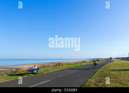 Mann sitzt auf einer Bank am Strand von Thornton Cleveleys in den frühen Morgenstunden, North Blackpool, Lancashire, UK Stockfoto