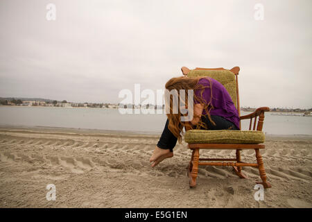 Portrait von junge Frau sitzt im Stuhl am Strand Stockfoto
