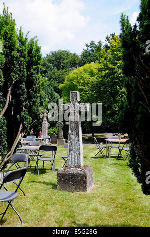 Keltisches Kreuz umgeben von Tischen und Stühlen im Kirchhof von Str. Marys Kirche, Bayford Hertfordshire Stockfoto