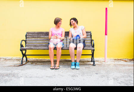 Zwei Frauen sitzen auf Bank und sprechen Stockfoto