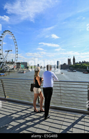 Ein junges Paar, Blick auf die Houses of Parliament, Themse und London Eye von Hungerford Bridge Stockfoto