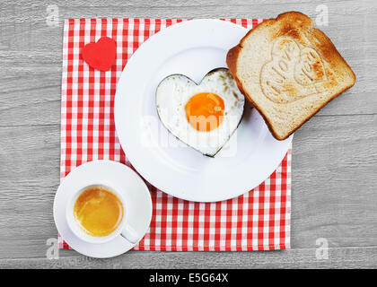 Spiegelei in Herzform und Toast mit Liebesbotschaft. Frühstück für einen lieben Menschen Stockfoto