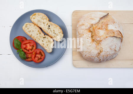 Platte mit Scheiben Brot, Tomaten und Basilikum bereit für eine italienische bruschetta Stockfoto