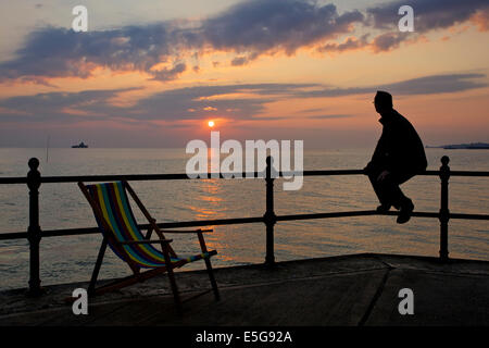 Hampton in der Nähe von Herne Bay, Kent, UK 31. Juli 2014. Eine trübe Sonnenaufgang in Hampton in Kent. Ein Mann schaut die Ansicht mit den Ruinen von Herne Bay Pier sichtbar, die von Stürmen in den 1970er Jahren zerstört worden war. Das sonnige Wetter wird voraussichtlich bis Samstag bleiben beim Duschen für den Südosten prognostiziert werden. Stockfoto