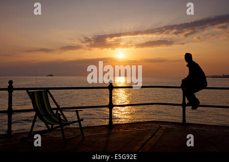 Hampton in der Nähe von Herne Bay, Kent, UK 31. Juli 2014. Eine trübe Sonnenaufgang in Hampton in Kent. Ein Mann schaut die Ansicht mit den Ruinen von Herne Bay Pier sichtbar, die von Stürmen in den 1970er Jahren zerstört worden war. Das sonnige Wetter wird voraussichtlich bis Samstag bleiben beim Duschen für den Südosten prognostiziert werden. Stockfoto