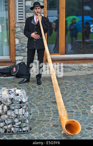 Ein Busk, ein Alphorn zu spielen, in der Straße von der Schweizer Stadt von Nendaz. Stockfoto