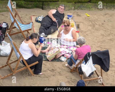 Applying Familiengruppe genießen ein Picknick auf einer geschützten Ecke des Whitby Weststrand Stockfoto