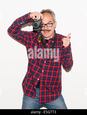 Modefotograf Typ mit Schnurrbart trägt kariertes Shirt mit einer Kamera halten und ein Foto machen, während Daumen hoch. Stockfoto