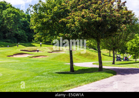 Vier männliche Golfer spielen auf einem Golfplatz in der Nähe von Bunkern. Stockfoto