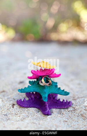 Gold Trauringe auf Farbe Seesterne am weißen Strand. Hochzeit Urlaub Konzept Stockfoto