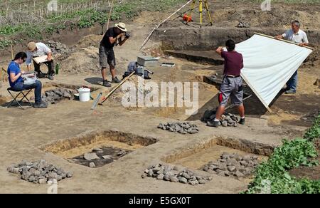 Sachsen-Anhalt, Deutschland. 31. Juli 2014. Ausgrabung Arbeiter dokumentieren die Lage der Entdeckung von der Feuerstelle in der Nähe von Worbzig, Deutschland, 31. Juli 2014. Hier wurde ein rund 3000 Jahre alten Fleisch verarbeitenden Anlage aus der Bronzezeit entdeckt. Die 10.000 Quadratmeter großen Fläche ist gespickt mit 57 Feuerstellen sowie rund 1.000 Schwein Knochen und Keramik. Es ist die einzige Anlage in Mitteldeutschland bis jetzt gefunden. Die Salz Keramik ist auch Beweis dafür, dass Salz vor Ort hergestellt wurde. Geräuchertes Fleisch kann für mehrere Wochen und gesalzenem Fleisch gehalten werden, für mehrere Jahre. © Dpa picture-Alliance/Alamy Live News Stockfoto