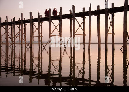 Mönche, die Kreuzung Taungthaman See auf das Teakholz U Bein Brücke, Amarapura, Myanmar (Burma). Stockfoto