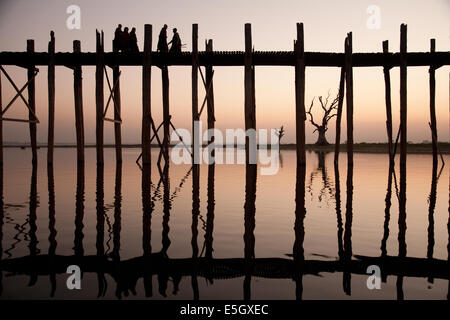 Mönche, die Kreuzung Taungthaman See auf das Teakholz U Bein Brücke, Amarapura, Myanmar (Burma). Stockfoto