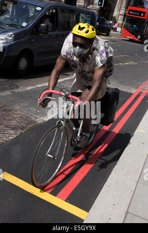 Radfahrer rast durch die City of London, sein Fahrrad und Helm passend die gelben und roten Linien auf neuen Asphalt. Stockfoto