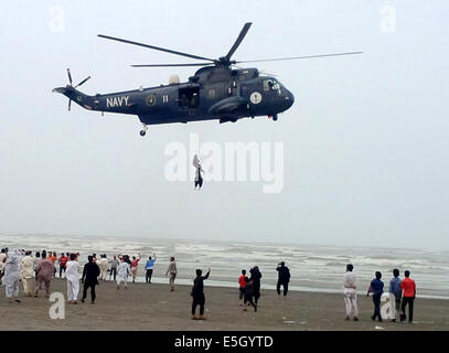 Karachi. 31. Juli 2014. Pakistan Marine Sea King Hubschrauber ist mit einem Froschmann, befestigt an einer Winde aus dem Flugzeug, die einen wiederhergestellten Körper ein ertrinkendes Opfer über Clifton Beach im südlichen Hafenstadt pakistanischen Stadt Karachi am 31. Juli 2014 transportiert gesehen. Mindestens 19 Leichen der Opfer wurden wiederhergestellt, nachdem sie beim Baden im Meer in der Nähe von Pakistans südlichen Hafen Stadt Karachi am Mittwoch, ertrunken war, berichteten lokale Medien. © Arshad/Xinhua/Alamy Live-Nachrichten Stockfoto